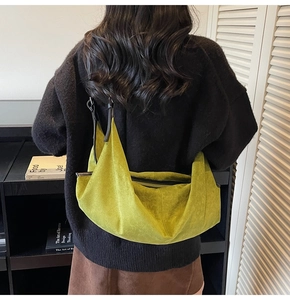Close-up of a bright green suede hobo bag with black leather trim and crossbody strap