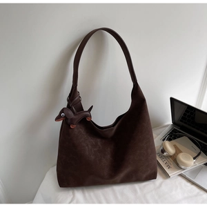 Detail of a dark brown hobo tote bag with a cute dachshund charm in a lifestyle setting