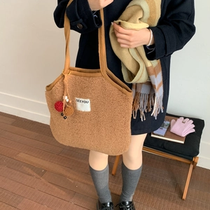 Close-up of brown lamb wool tote bag with SEEYOU label and decorative pompom charm