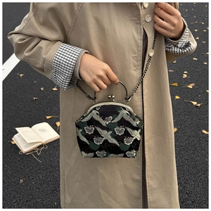 Detail of crane embroidery on retro crossbody bag with golden metal handle and frame