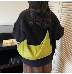 Detailed back view of a moss green suede hobo bag worn by a model in a studio setting