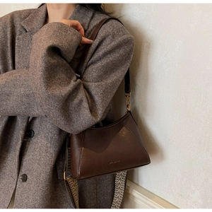 Detail of dark brown leather underarm bag with decorative geometric woven shoulder strap