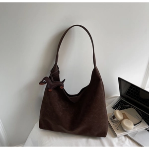 Detail of dark brown matte hobo shoulder bag with a dachshund charm on an office desk