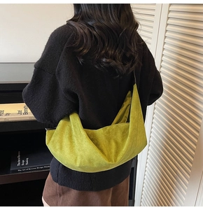 Detailed view of moss green suede hobo bag shown on a model in a cozy library setting