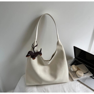 Close-up of matte off-white hobo bag with a brown dachshund dog charm on white fabric