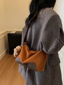 Dunkelbraune Suede-Handtasche mit Lederbesatz und Bären-Anhänger am Wollmantel