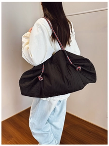 Détail d'un grand sac hobo noir avec une bandoulière unique en corde tressée tricolore