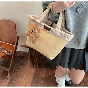 Detail of yellow canvas tote bag with off-white faux shearling trim and cute bear charm