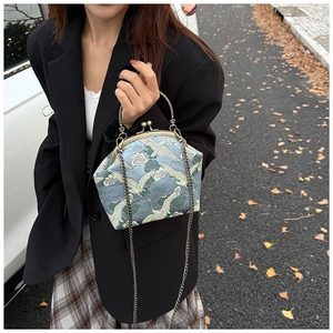 Detail of crane embroidery and vintage metal clasp on a blue brocade crossbody bag