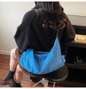 Detail of blue suede hobo bag featuring streamlined silhouette and black edge contrast
