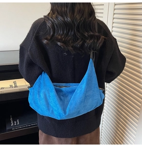 Detail view of the soft blue suede hobo bag shown worn as an underarm shoulder bag