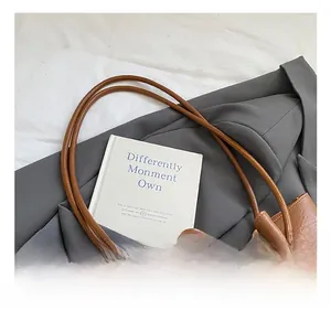 Detail eines braunen Leder-Shoppers mit Knotendesign auf einem grauen Sakko