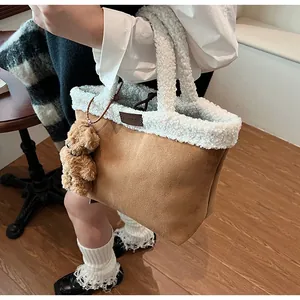 Close-up of a brown suede tote bag with white plush fur trim and a cute bear charm