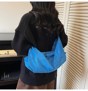 Detail view of the royal blue suede crossbody hobo bag on model in a cozy library