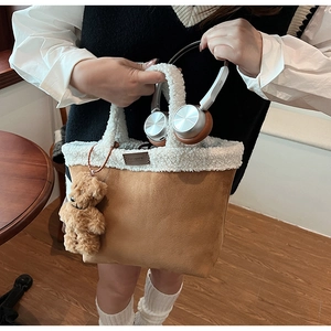 Detailed shot of brown suede tote bag with white faux fur trim and cute bear charm