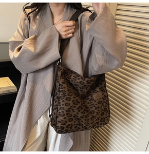 Detail view of large leopard print canvas tote bag with adjustable wide strap on a model
