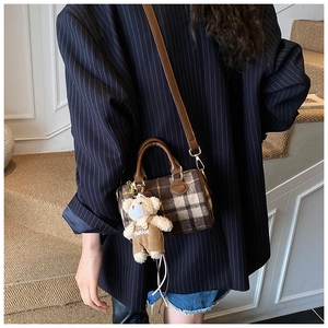 Brown plaid boston bag with bear charm shown from a high angle on a stylish staircase
