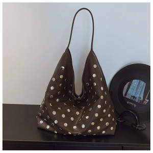 Detail of dark brown leather tote with silver studs and a retro rock style design