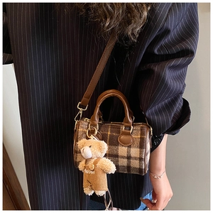 Close-up of retro plaid Boston bag with leather handles and cute bear charm detail