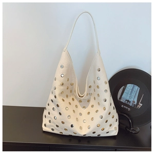 Macro shot of minimalist hobo bag featuring dual-tone gold and silver metal rivets