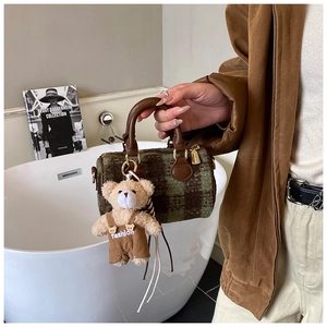 Close-up of mini plaid tote bag with brown leather handles and a cute teddy bear charm