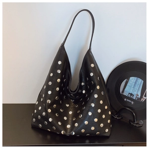Detail view of black leather tote bag with silver metal studs and vinyl record props