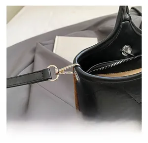 Detail showing silver lobster clasp, zipper, and quilted black leather on tote bag