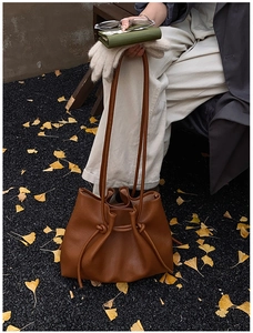 Detail einer dunkelbraunen Vintage-Schultertasche auf goldenen Ginkgoblättern