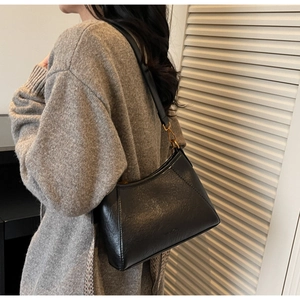 Detailed view of the black textured leather shoulder bag with matte gold hardware and stitching