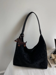 Minimalist black matte tote bag with shoulder strap and small dog charm accessory