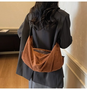Detailed back view of model wearing a caramel suede shoulder bag with hobo silhouette