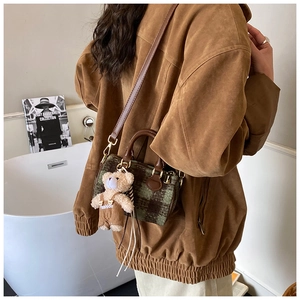 Detail of plaid boston bag with teddy bear charm and adjustable leather shoulder strap