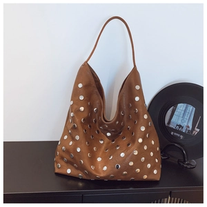 Close-up of brown leather hobo bag with silver rivets and vintage aesthetic