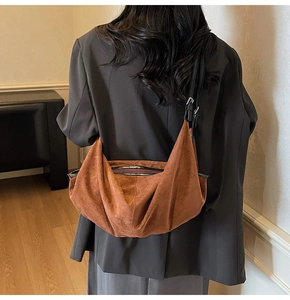 Detail of vintage brown suede crescent bag with black leather strap on model back