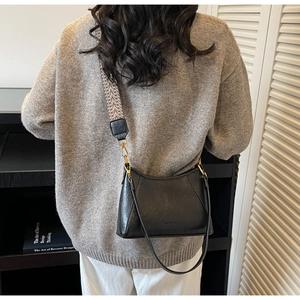 Detail of black vintage hobo bag with ethnic pattern wide strap on a grey sweater