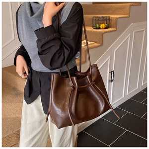 Detail of a dark brown vintage tote bag featuring a drawstring design and knotted strap