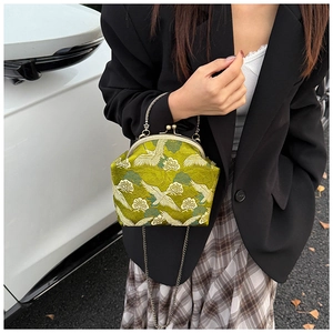 Close-up of green embroidery bag with white crane patterns and bronze metal clasp