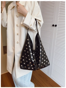 Close-up of black leather tote bag with silver metal rivets and vintage stud detailing