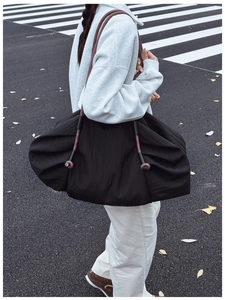 Détail du grand sac cabas plissé noir avec bandoulière en corde tressée rouge et gris
