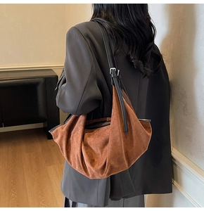 Detail of a brown suede shoulder bag with black leather strap and metal buckle