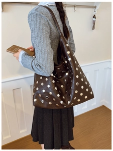 Close-up of vintage dark brown tote bag with decorative silver rivets and wide strap