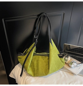 Macro view of green suede tote bag showing texture and black leather strap details