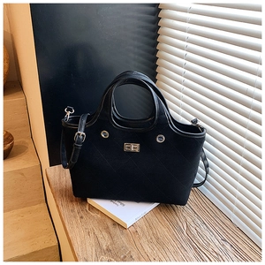 Close-up of black quilted tote bag with matte finish and metallic square buckle detail