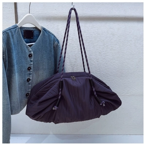 Détail d'un sac cabas plissé violet foncé montrant la texture et la bandoulière en corde