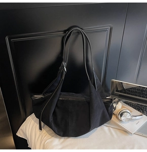 Close-up of a black oversized suede tote bag with laptop and headphones for urban commute