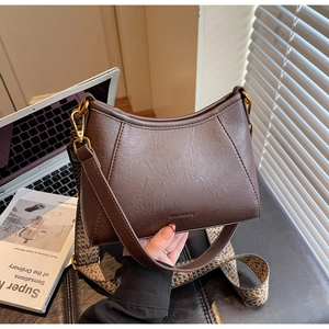 Detail of vintage brown crescent hobo bag with pebbled leather and ethnic woven strap