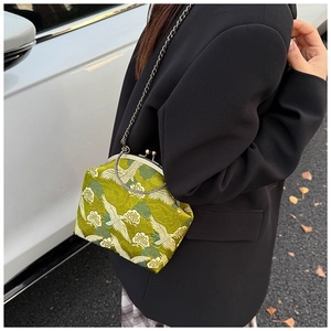 Detailed macro view of green silk embroidery on vintage crane pattern kiss-lock purse