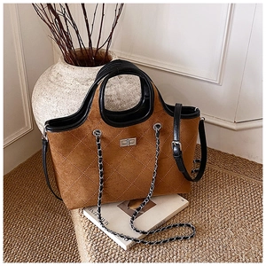 Detail of a brown quilted suede tote bag with a silver twist lock and black leather trim