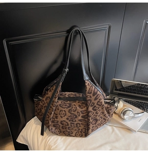 Detail of leopard print suede tote bag with slim black leather straps and zipper