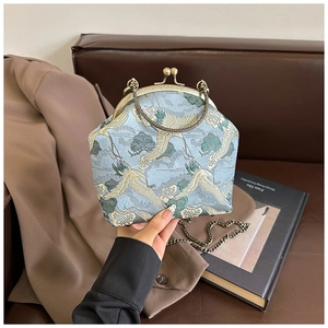 Detailed view of light blue embroidery bag with crane pattern and bronze clasp